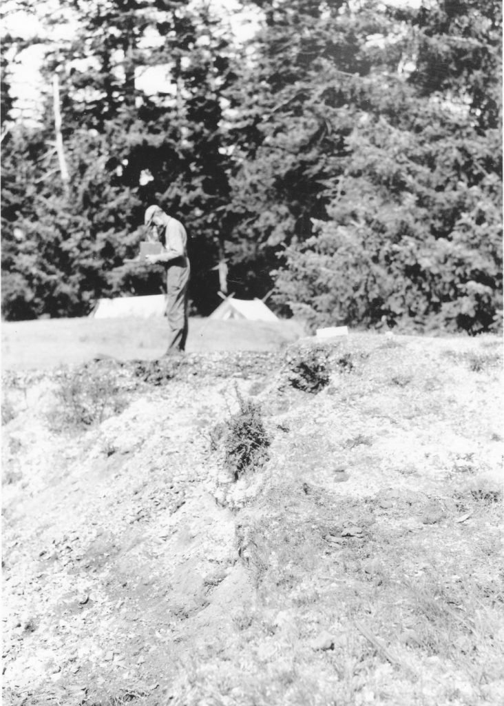 Laing taking photos of his homesite, with campsite in background, 1922